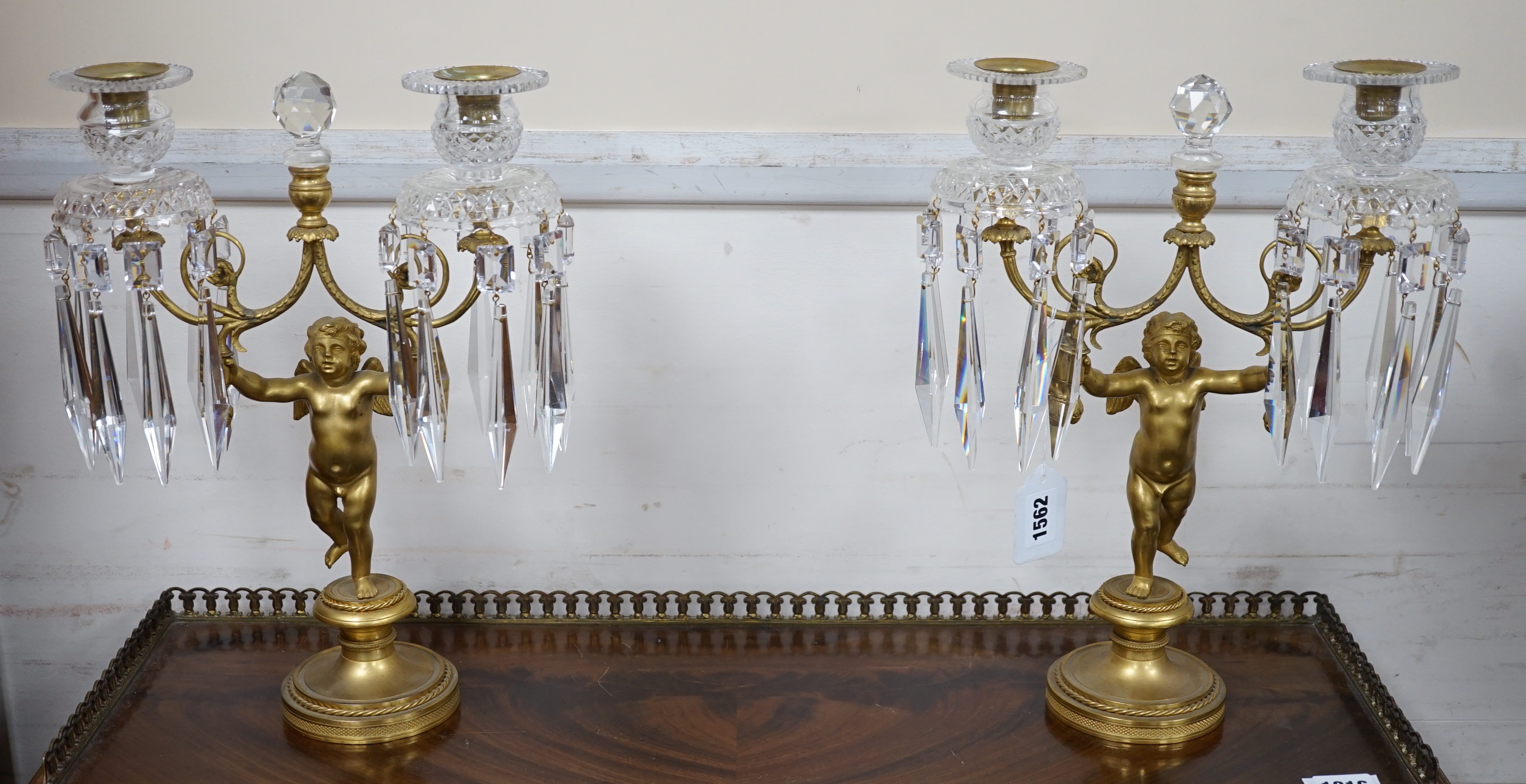 A pair of Regency ormolu ‘Cupid’ two branch glass lustre candelabra, 37cm high